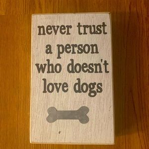 White wooden plaque says “never trust a person who doesn’t love dogs”